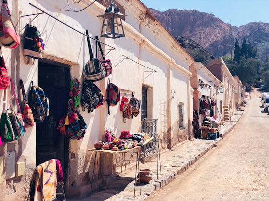 assorted clothes hanged on clothes line near houses and mountain during daytime in Purmamarca Argentina