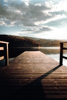 A quiet dock stretching into calm lake waters under a soft morning sky.