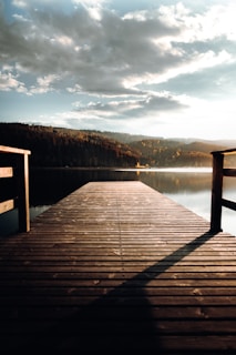 A quiet dock stretching into calm lake waters under a soft morning sky.