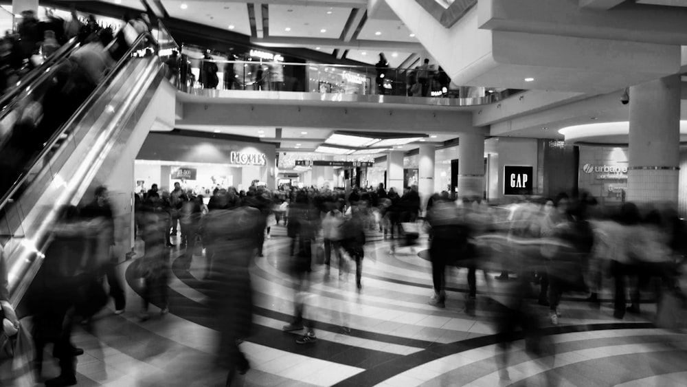 people walking inside building grayscale photo