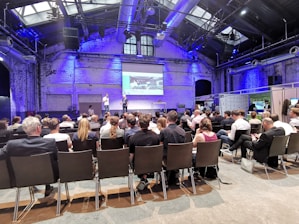 Picture of a lively conference with engaged attendees and a speaker on stage