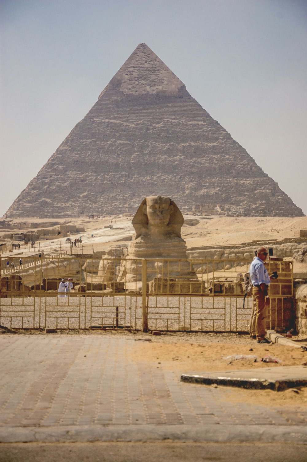 man in brown jacket standing near pyramid during daytime