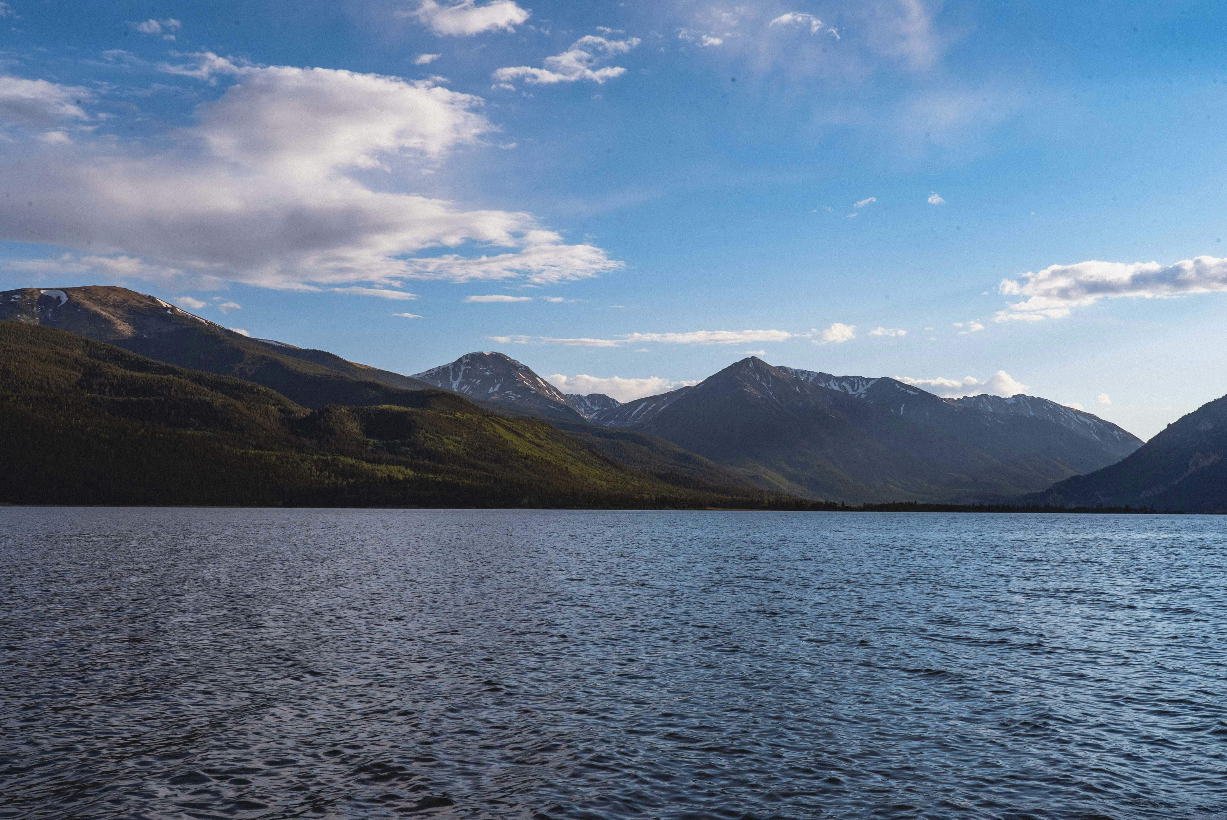 body of water near mountain under blue sky during daytime