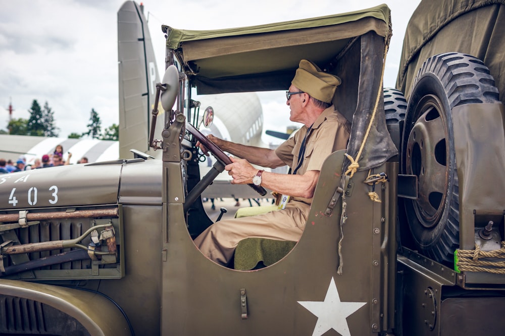 man in brown and black camouflage uniform sitting on vintage car