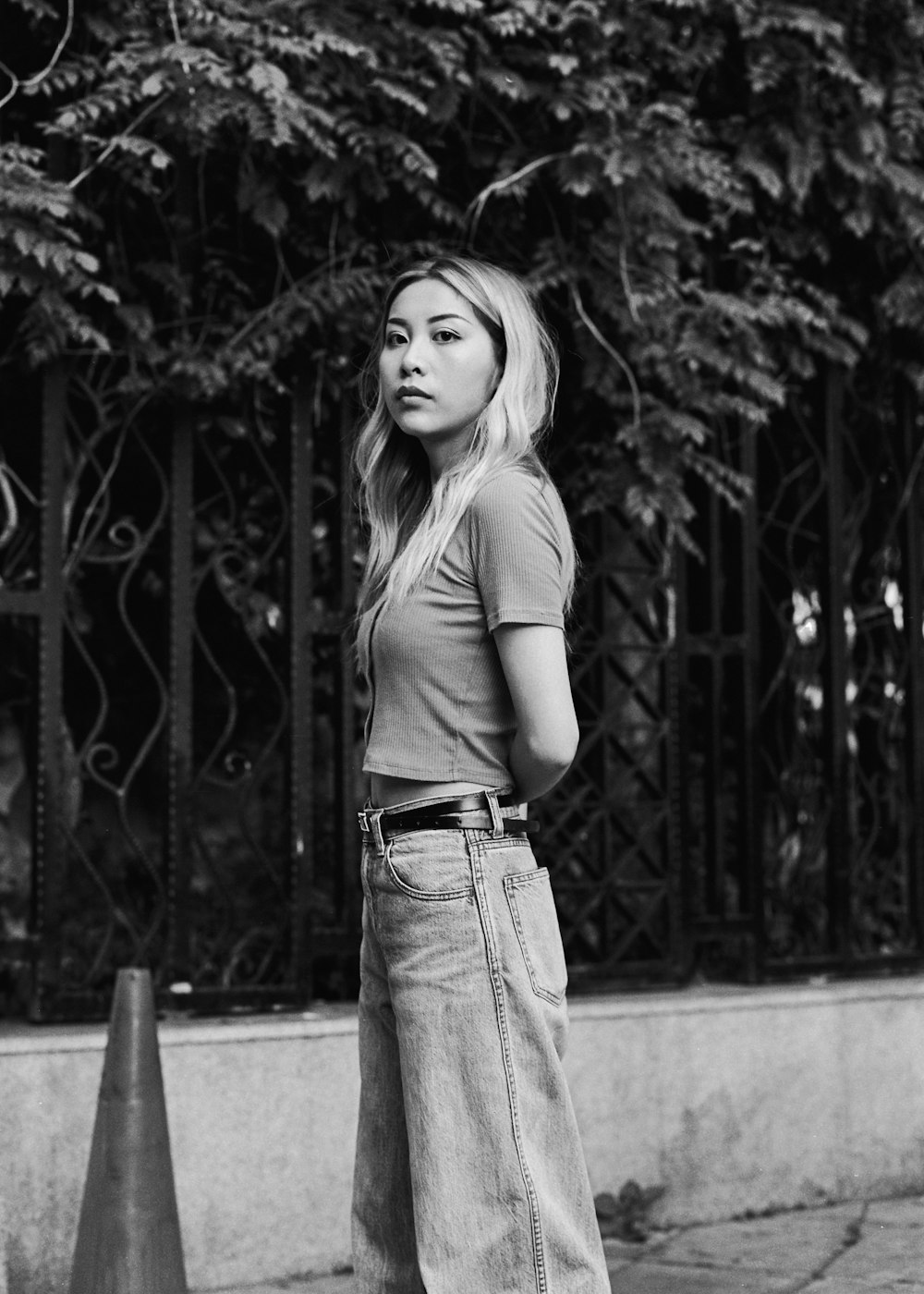 woman in gray shirt and blue denim jeans standing on sidewalk