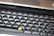 A close-up view of a computer keyboard, featuring a standard layout with English and additional non-Latin characters printed on the keys. The keys are mostly black with white and grey lettering, except for a few keys with orange symbols. The image is slightly out of focus, emphasizing a casual, everyday use context.