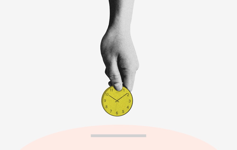 person holding yellow round analog clock
