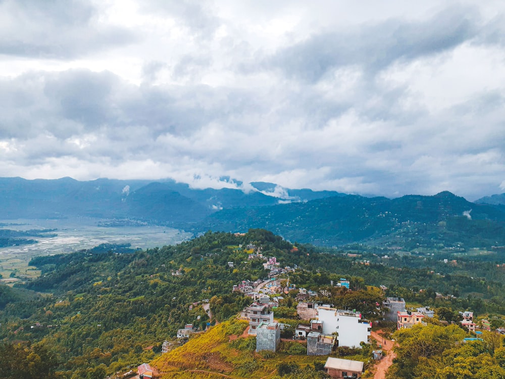 aerial view of city near green mountains under cloudy sky during daytime