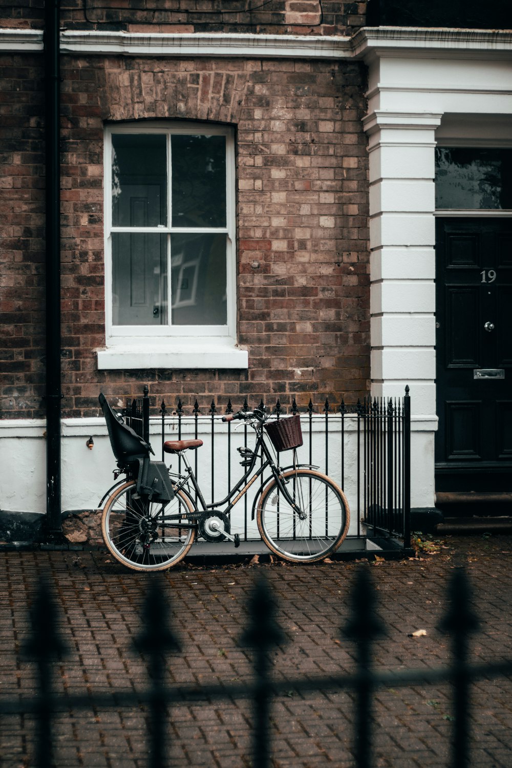 black city bike parked beside brown brick building