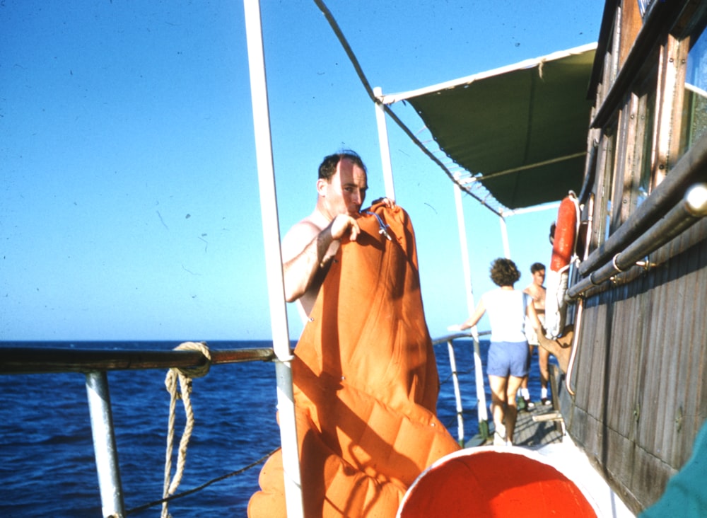 man in orange robe standing on boat during daytime