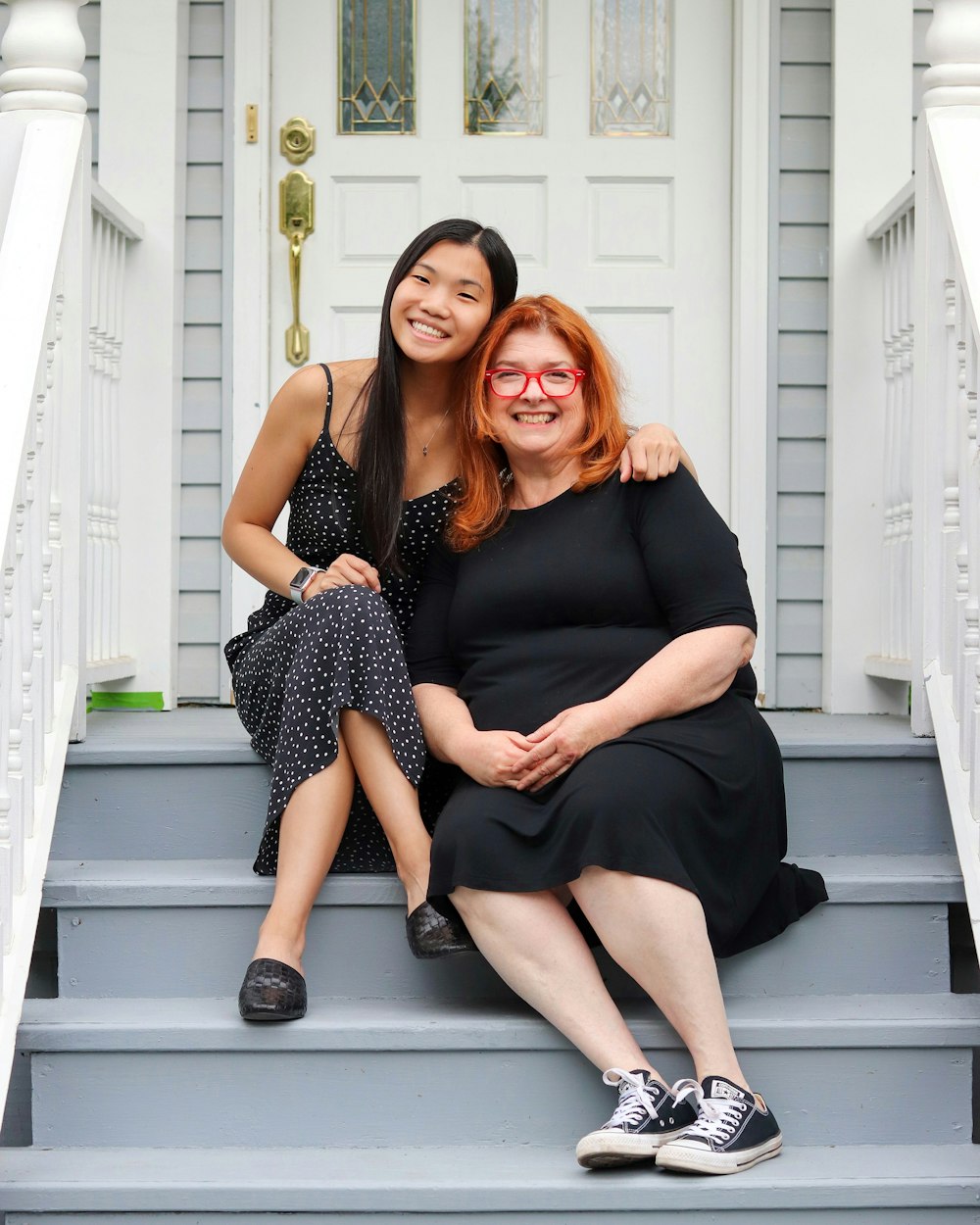 2 women sitting on white wooden bench