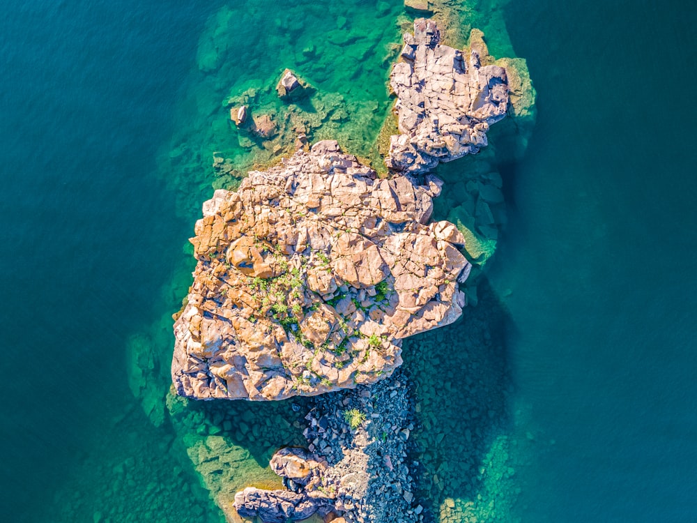 green and brown rock formation on body of water during daytime