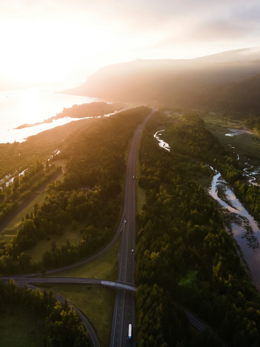 aerial view of road between green trees during daytime