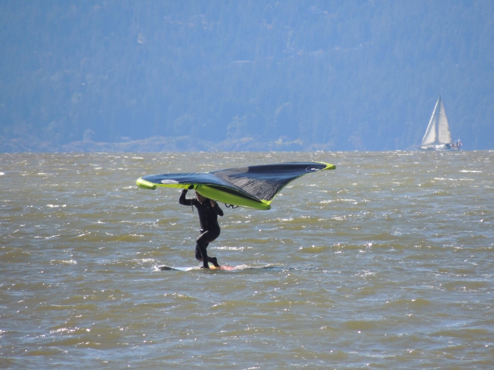 man in black wet suit holding green surfboard on water during daytime
