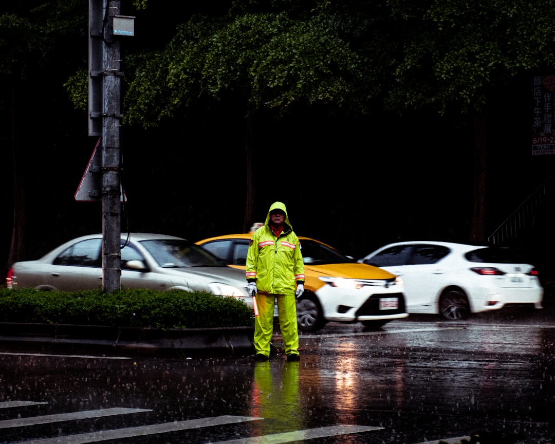 man in yellow jacket and black pants walking on street during night time