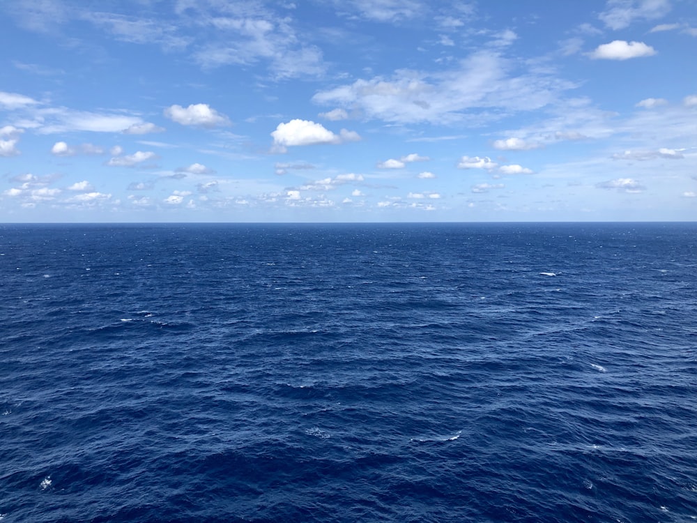 mar azul sob céu azul e nuvens brancas durante o dia