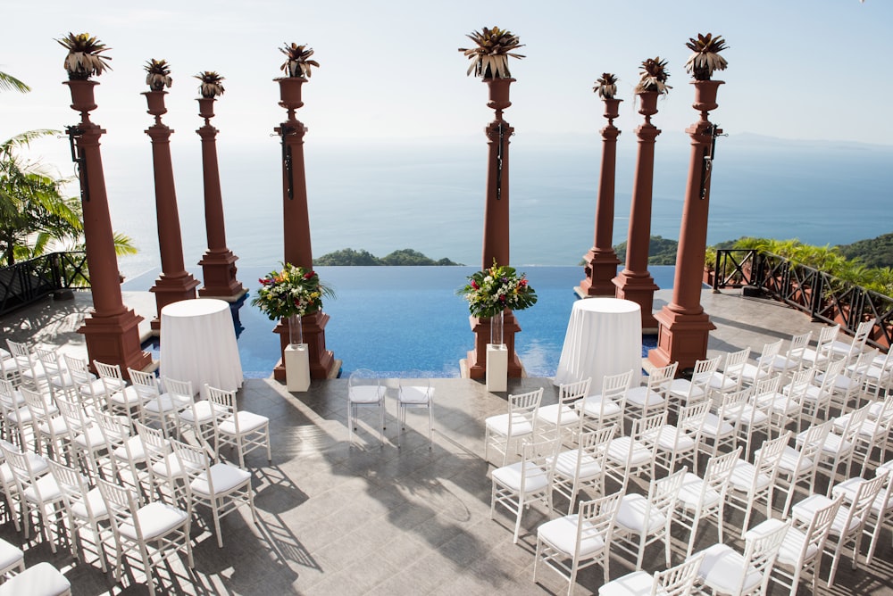 white wooden chairs on gray concrete floor near body of water during daytime