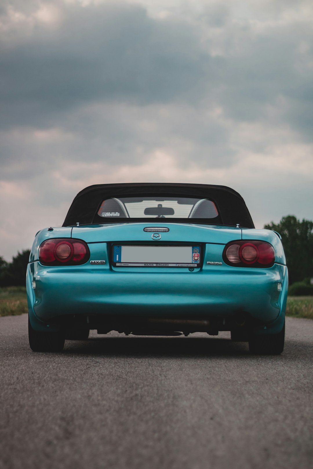 blue chevrolet camaro on road under gray clouds