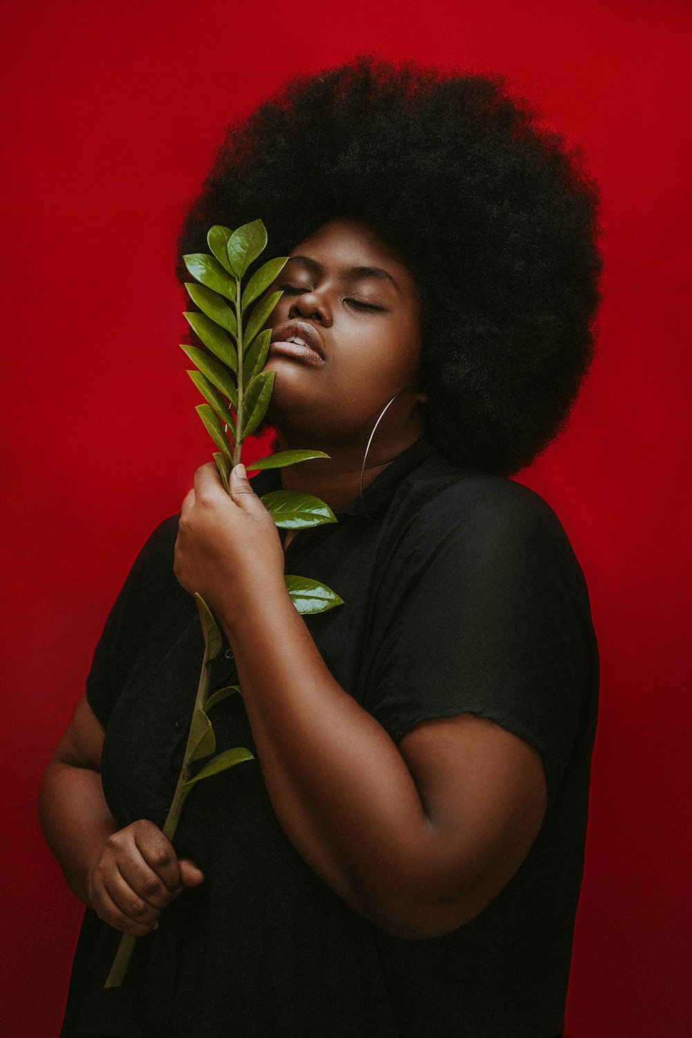 Femme en T-shirt à col rond noir tenant une plante verte