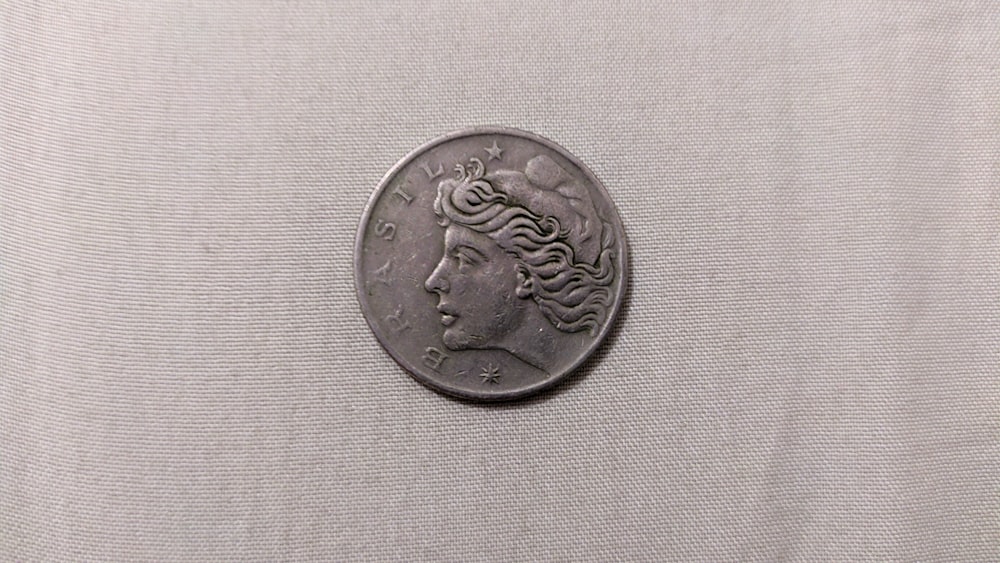 silver round coin on white textile