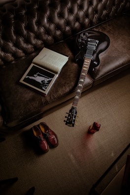 A candid photo of a guitar resting on a chair beside a notebook of handwritten lyrics.