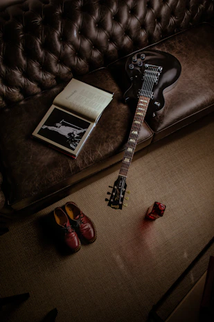 A close-up of a worn guitar resting beside an old notebook filled with handwritten lyrics.