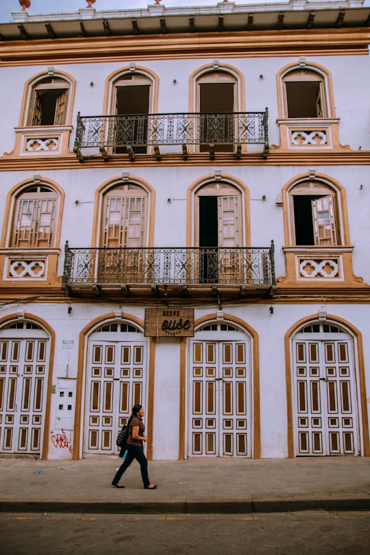 man in black jacket and blue denim jeans standing in front of brown concrete building during in Cuenca Ecuador