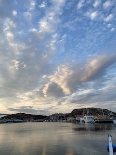 A cozy seaside village with charming boats docked under a golden sunset.