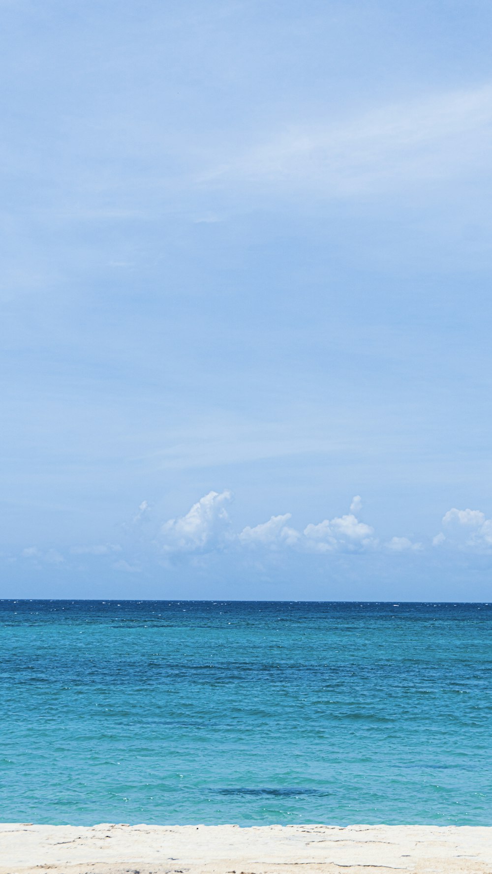 blue sea under blue sky and white clouds during daytime