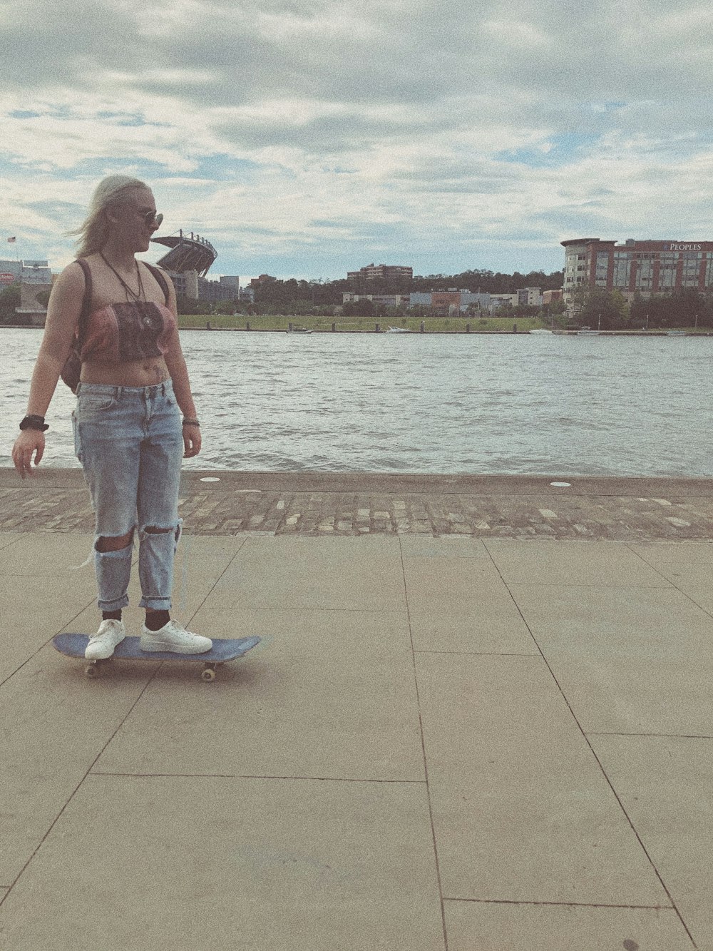 Mujer con camiseta sin mangas roja y jeans de mezclilla azules de pie en el muelle durante el día