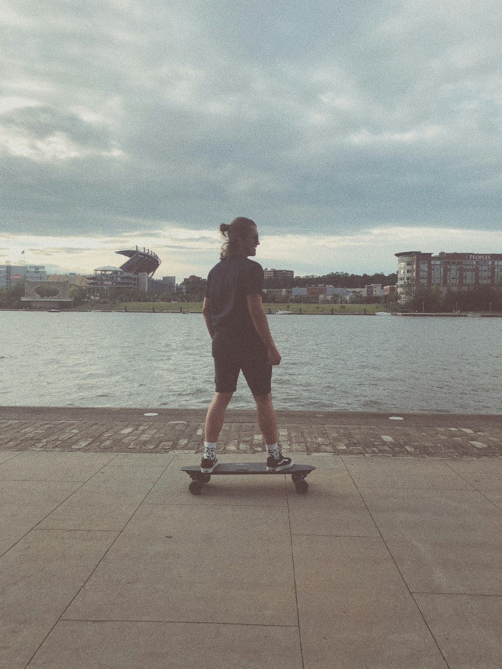 man in black shirt standing on gray and blue kick scooter during daytime