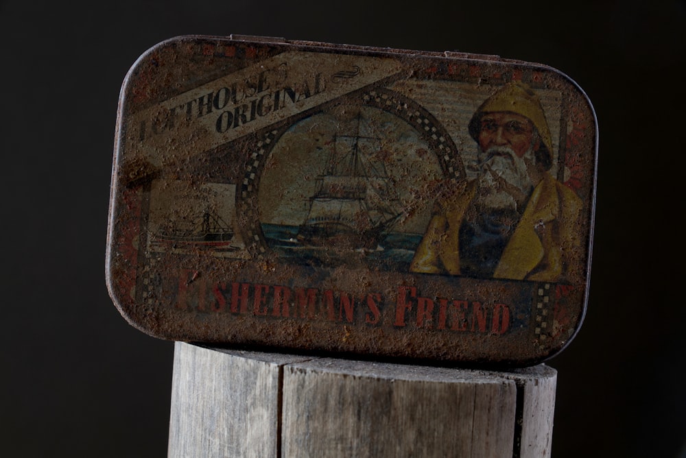 an old tin box sitting on top of a wooden post