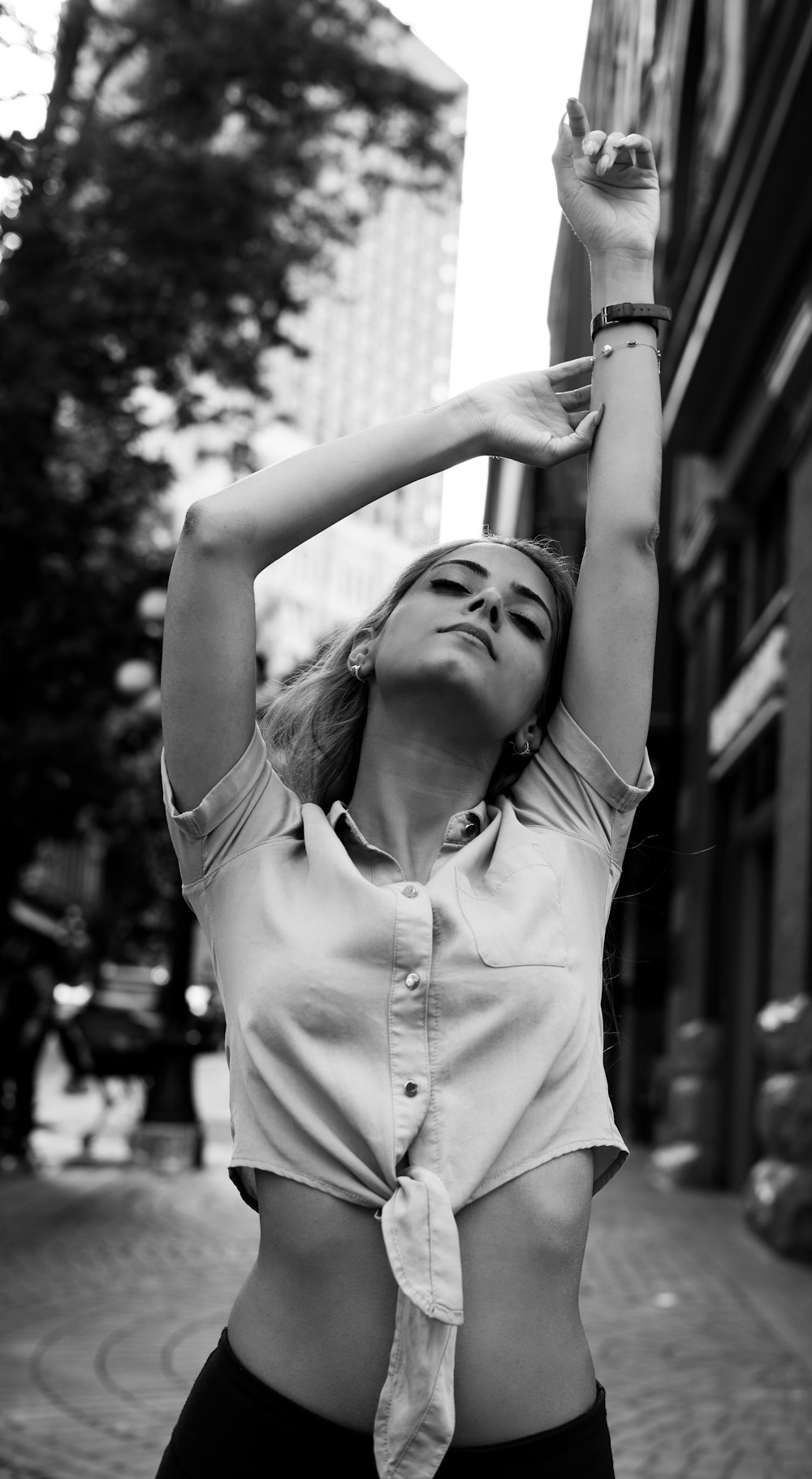 grayscale photo of woman in button up shirt raising her hands