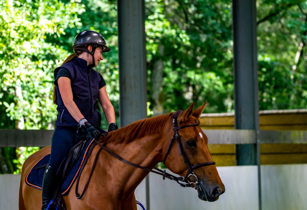 homme au casque noir chevauchant un cheval brun pendant la journée