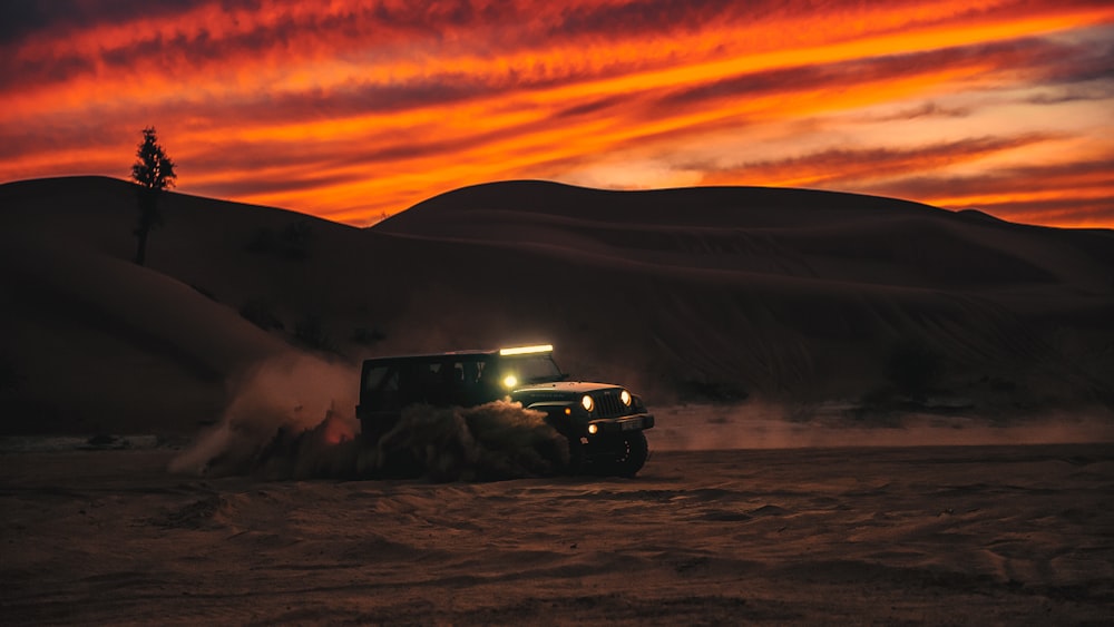 Schwarzer SUV auf schneebedecktem Feld bei Sonnenuntergang