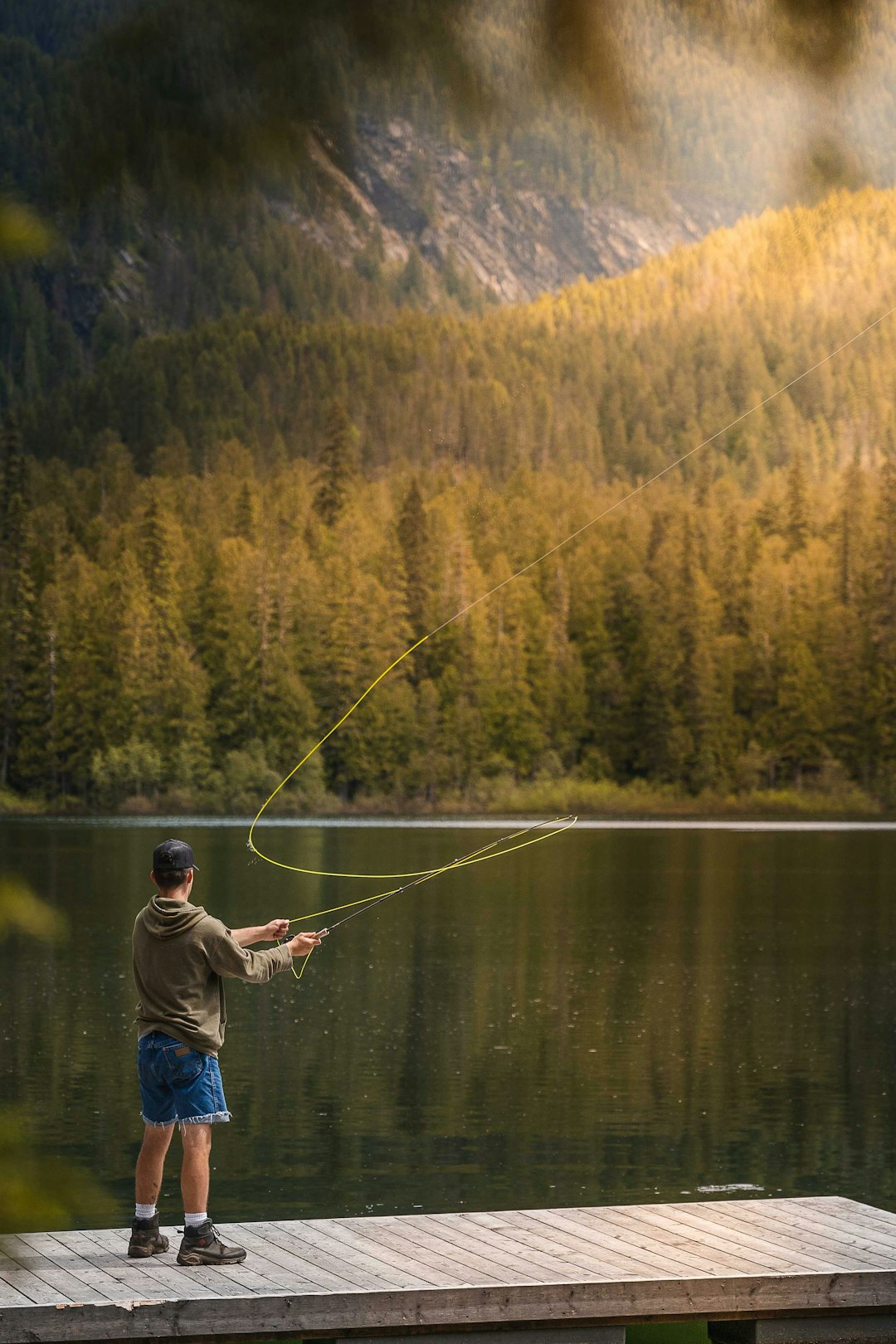 man in blue jacket fishing on lake during daytime