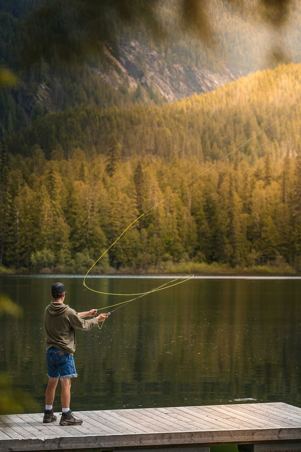 man in blue jacket fishing on lake during daytime