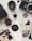 A collection of vintage photography equipment and photos on a light surface. There's a Pentax camera body, a camera lens, film canisters, a lens cap, and several instant photo prints. The photos depict casual scenes, including a person and a dog indoors.