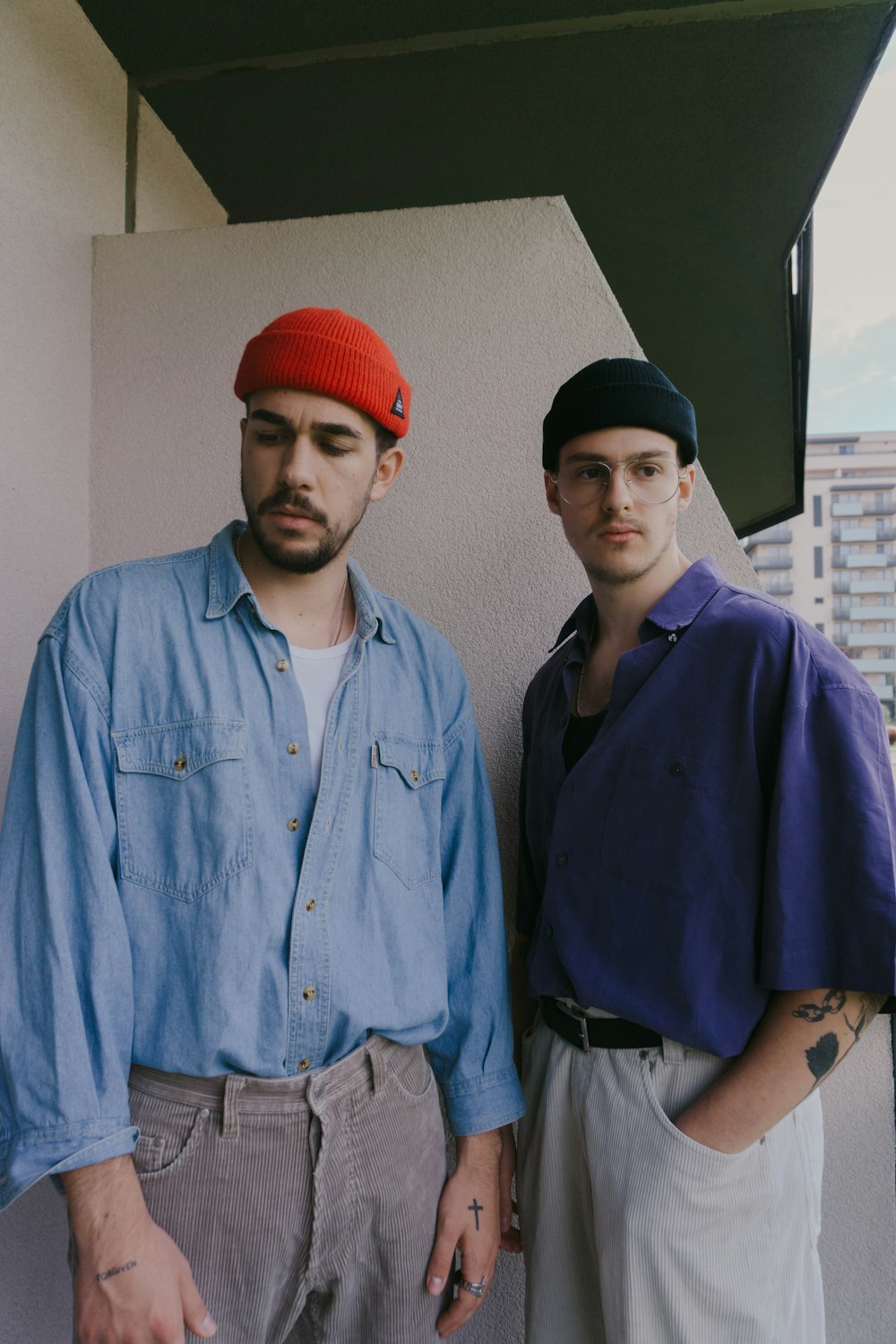 man in blue button up shirt standing beside man in red knit cap