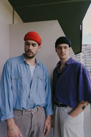 man in blue button up shirt standing beside man in red knit cap