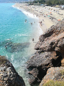 Bright sunny beach in Cape Town with turquoise waters and mountains in the background.