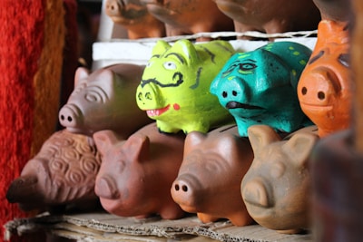 A collection of handcrafted decorative money banks in various shapes and colors.