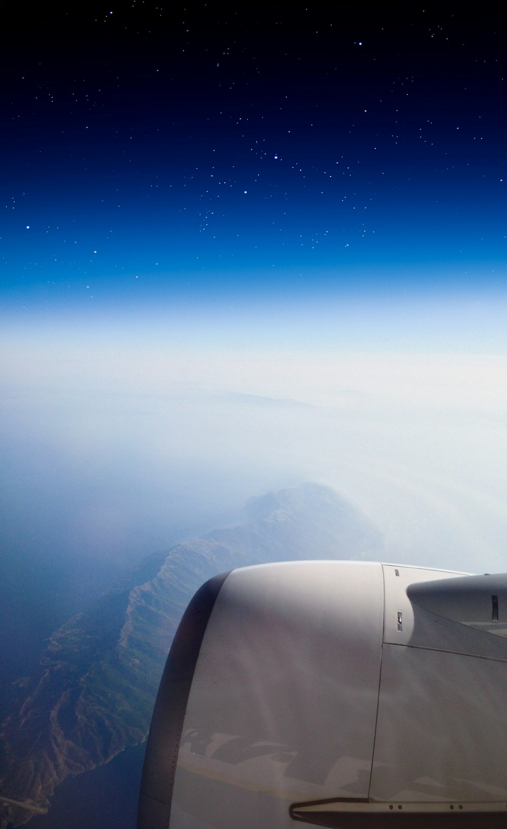 white airplane flying over the mountains during daytime