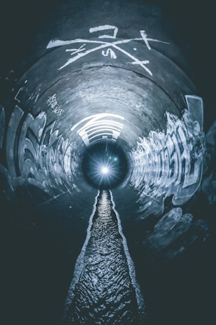 grayscale photo of tunnel with light