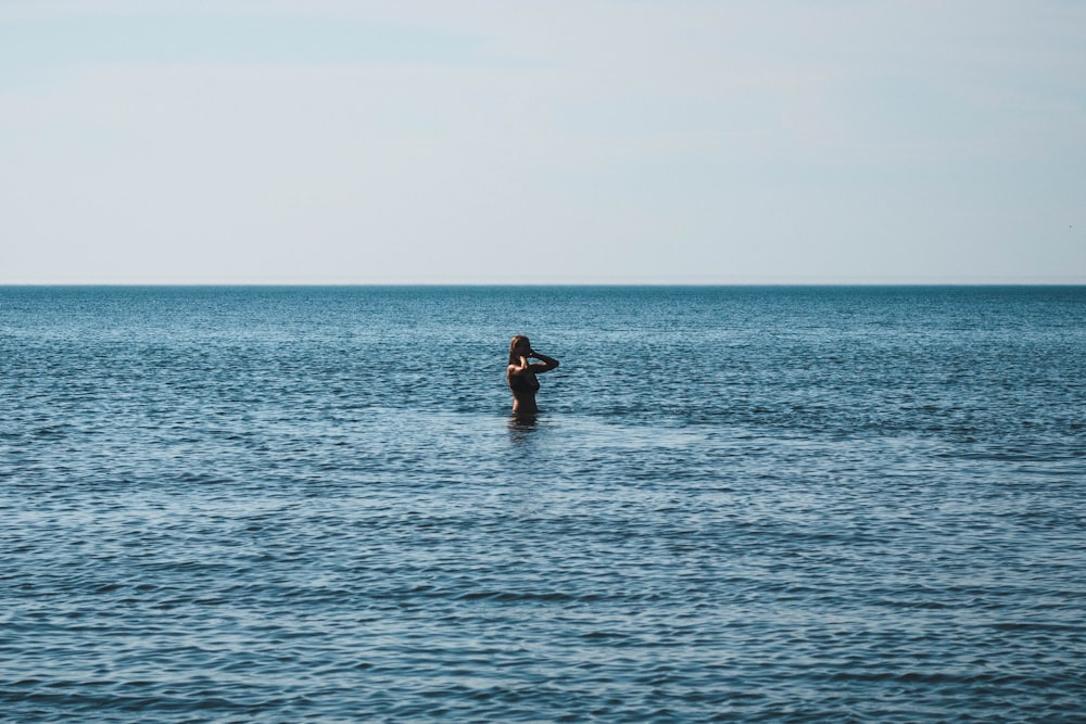 woman in black bikini on body of water during daytime