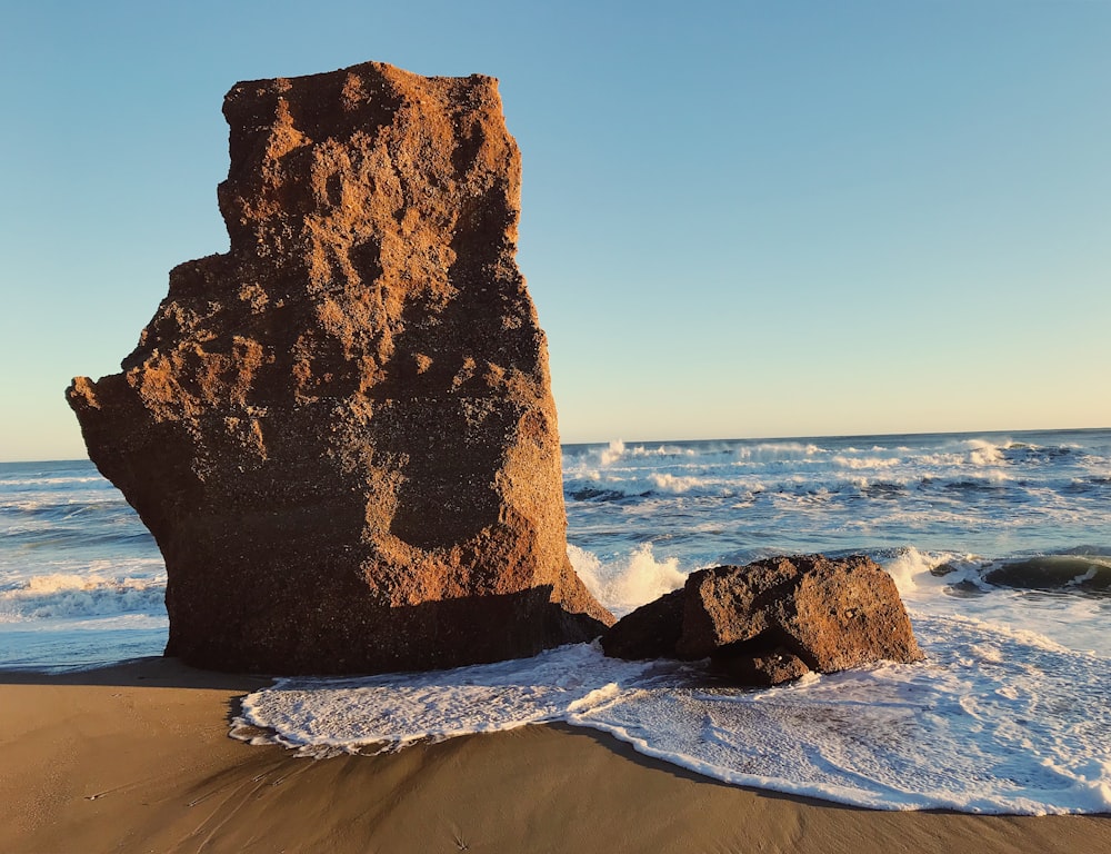 Formazione rocciosa marrone sulla spiaggia durante il giorno