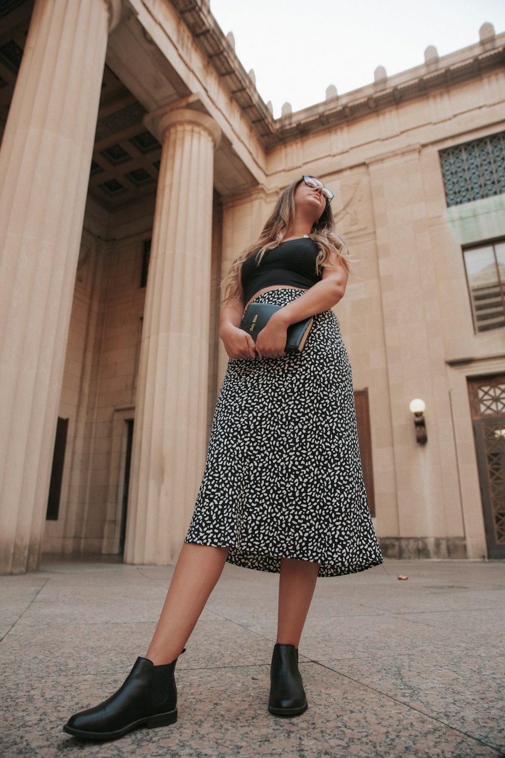 woman in black and white polka dot dress standing on gray concrete floor during daytime