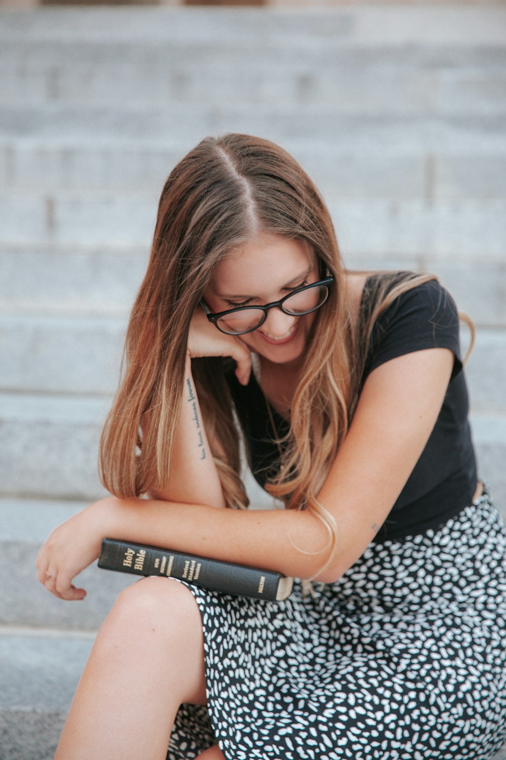 woman in black t-shirt and black and white pants sitting on concrete stairs