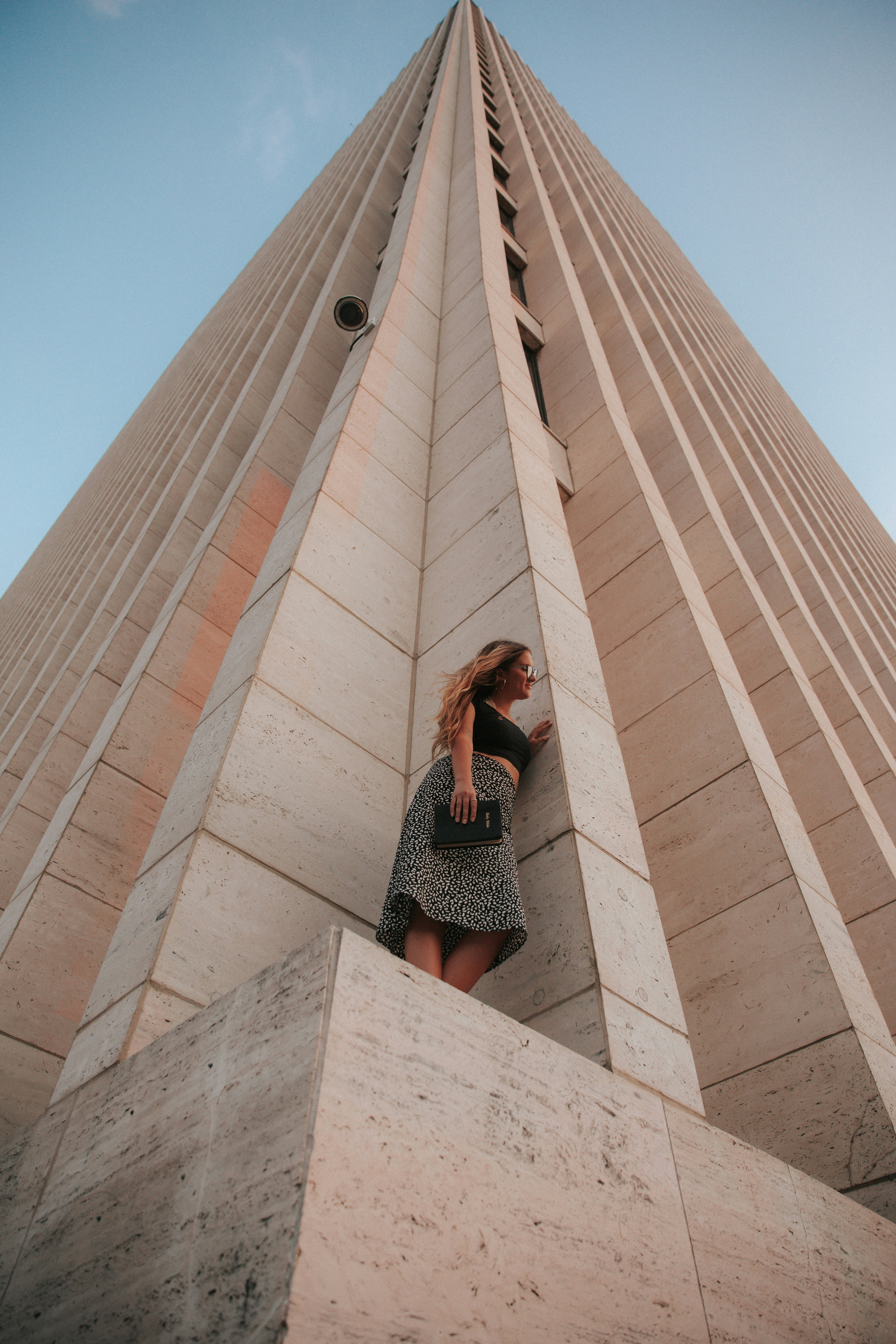 woman in black and white dress standing on brown concrete building during daytime