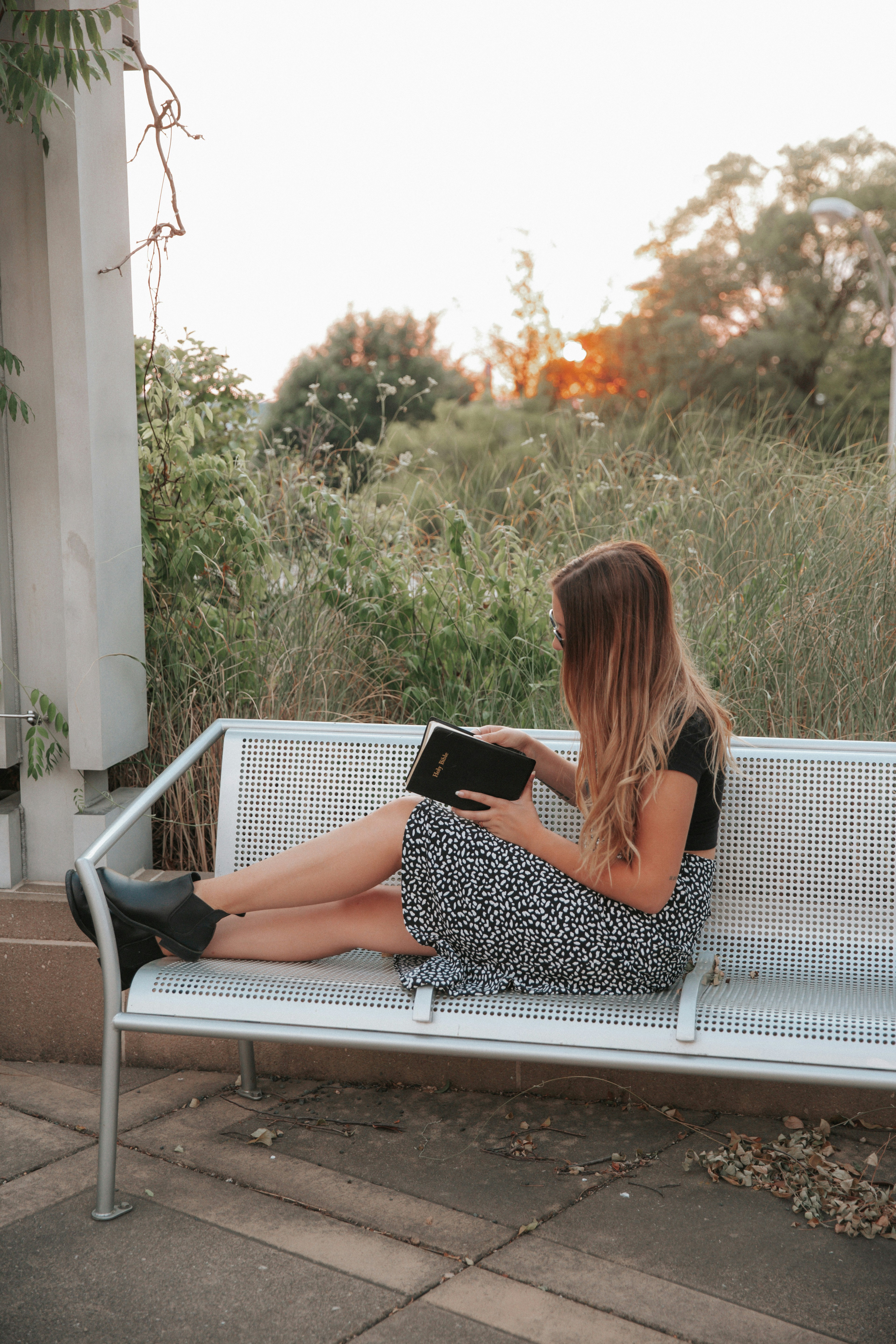woman in black and white polka dots dress sitting on white bench during daytime